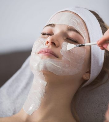 Beautician applying anzymatic peeling on woman's face in spa